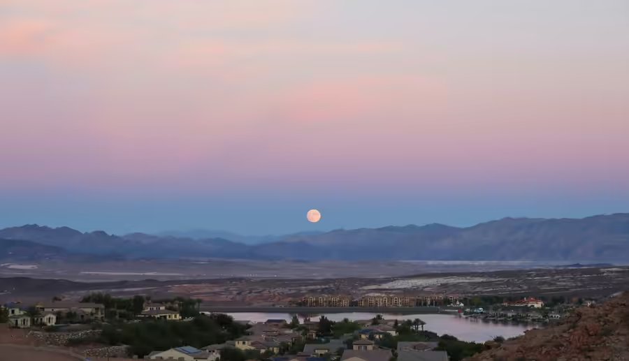 Lake Las Vegas al anochecer con luna llena saliendo sobre las colinas de Henderson